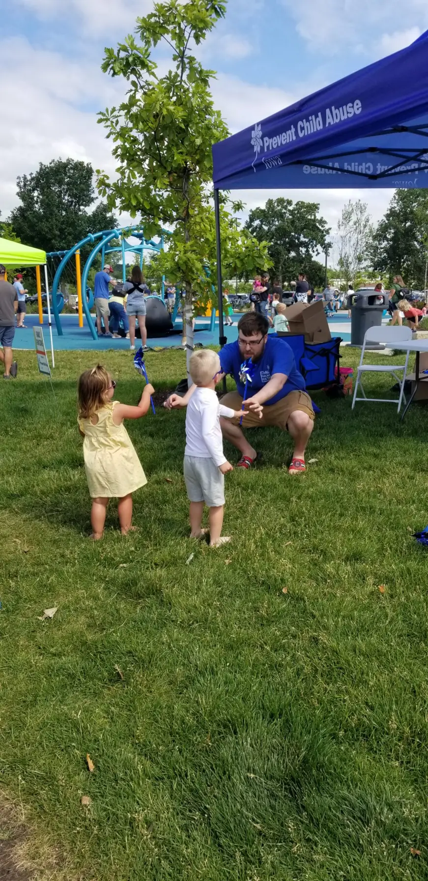 PCA Iowa volunteer sharing pinwheels with two small children.